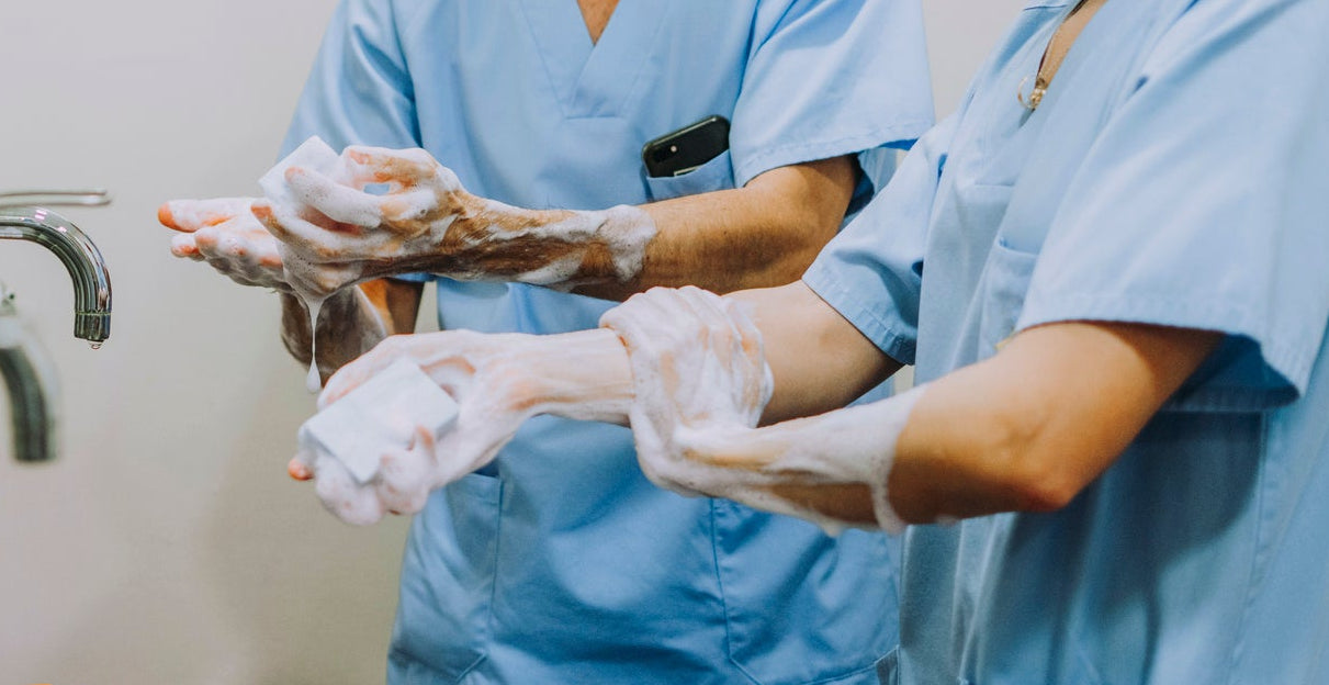 Two medical professionals in scrubs and masks washing their hands in a clinical setting with LabGUARD Anti-Microbial Hand Sop
